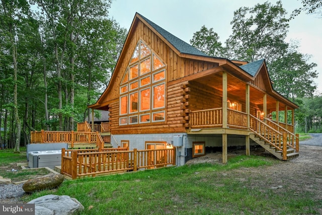 rear view of house featuring stairway, a hot tub, log exterior, and roof with shingles