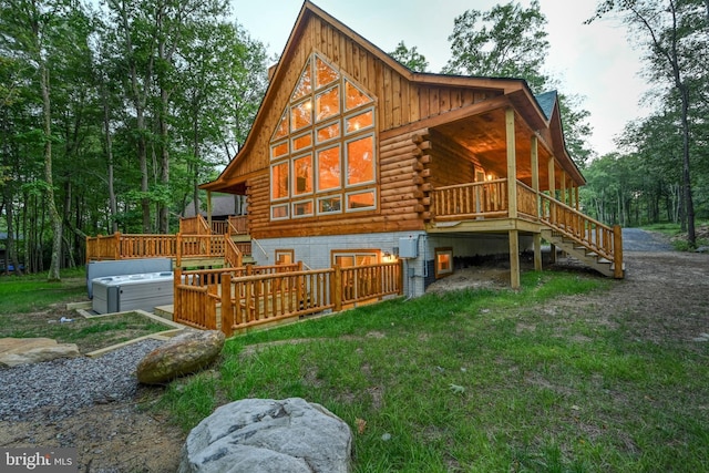 rear view of house with log exterior, stairway, board and batten siding, and a hot tub