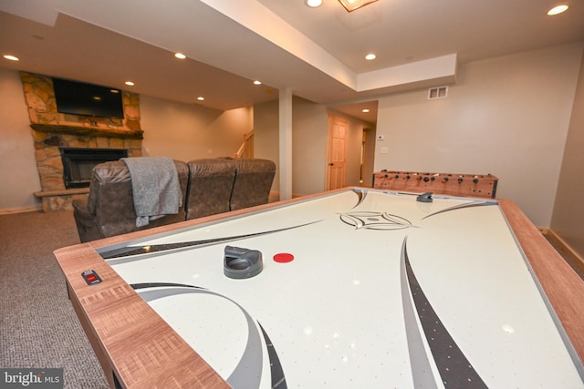 rec room featuring carpet floors, a stone fireplace, visible vents, and recessed lighting