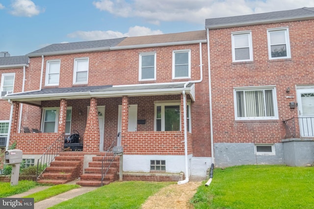 view of property featuring covered porch and a front lawn