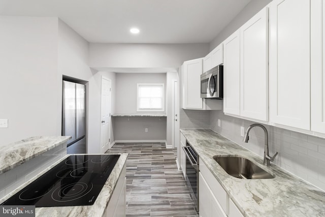 kitchen featuring hardwood / wood-style floors, sink, black electric cooktop, decorative backsplash, and light stone counters