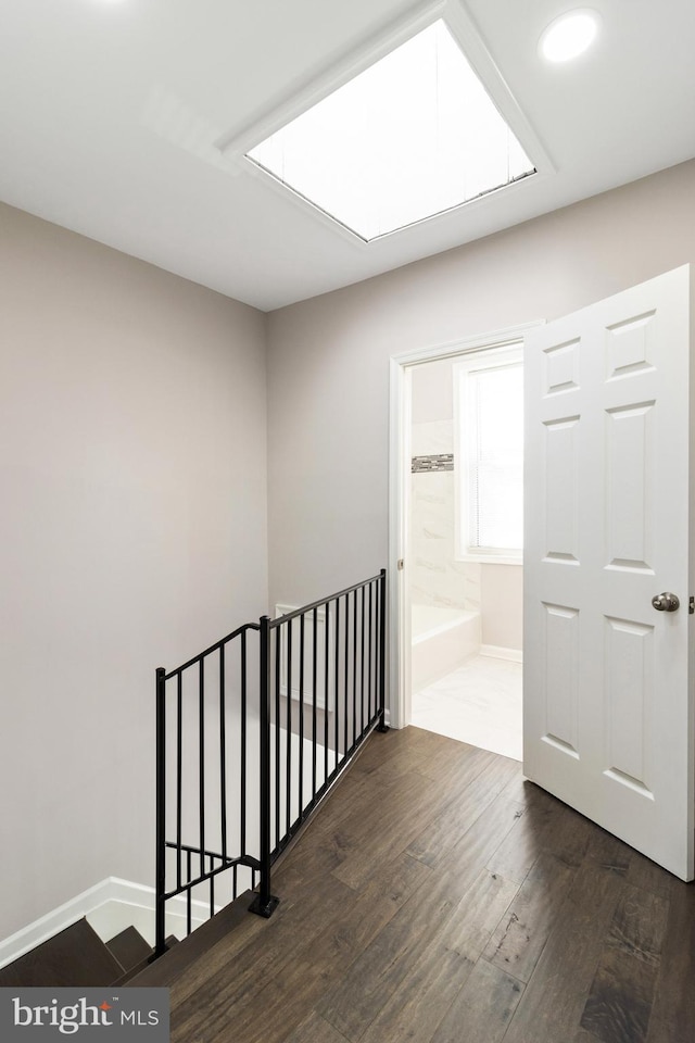 hallway with hardwood / wood-style flooring and a skylight