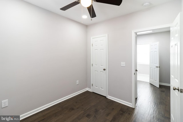 unfurnished bedroom with ceiling fan and dark wood-type flooring