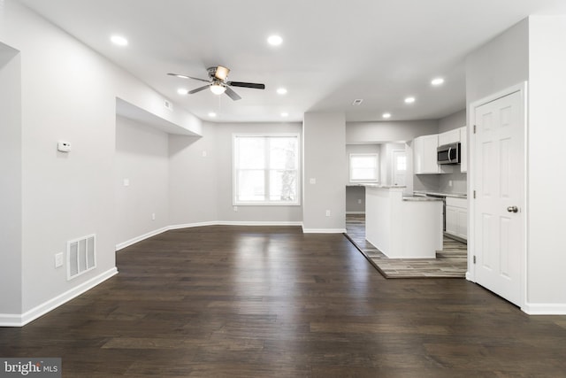 unfurnished living room featuring ceiling fan and dark hardwood / wood-style floors