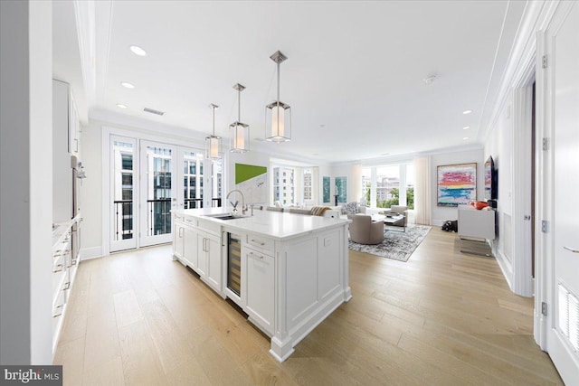 kitchen featuring light hardwood / wood-style floors, white cabinetry, ornamental molding, and wine cooler