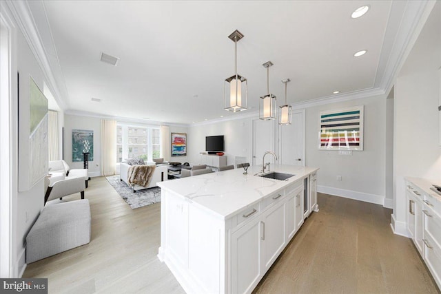 kitchen featuring light wood-type flooring, sink, light stone countertops, and white cabinets