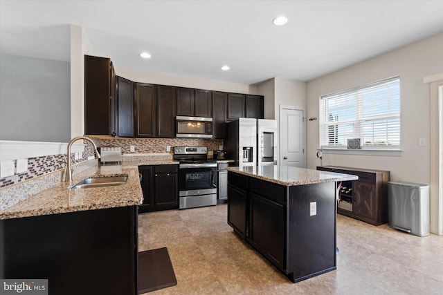 kitchen featuring sink, decorative backsplash, a kitchen island, light tile patterned floors, and stainless steel appliances