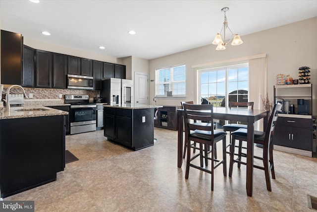 kitchen featuring light tile patterned flooring, sink, appliances with stainless steel finishes, tasteful backsplash, and pendant lighting