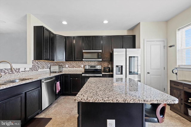 kitchen featuring backsplash, a center island, stainless steel appliances, and light stone counters