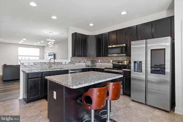 kitchen featuring stainless steel appliances, light hardwood / wood-style floors, tasteful backsplash, a kitchen island, and a breakfast bar