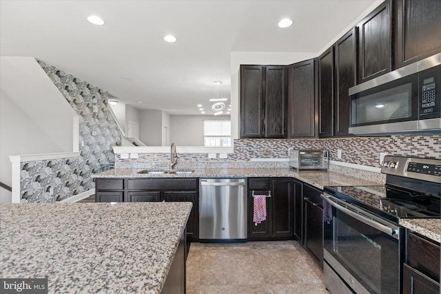 kitchen with sink, stainless steel appliances, tasteful backsplash, and light stone counters