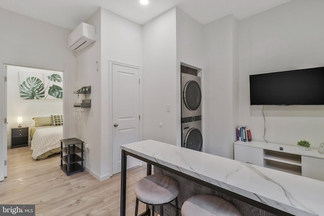 office featuring light hardwood / wood-style flooring, a wall mounted AC, and stacked washer and dryer