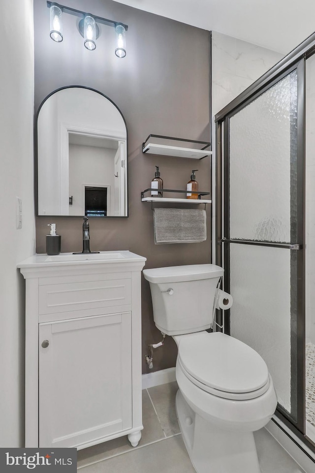 bathroom featuring vanity, a shower with door, toilet, and tile patterned flooring