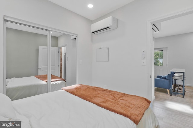 bedroom featuring an AC wall unit, light wood-type flooring, and a closet