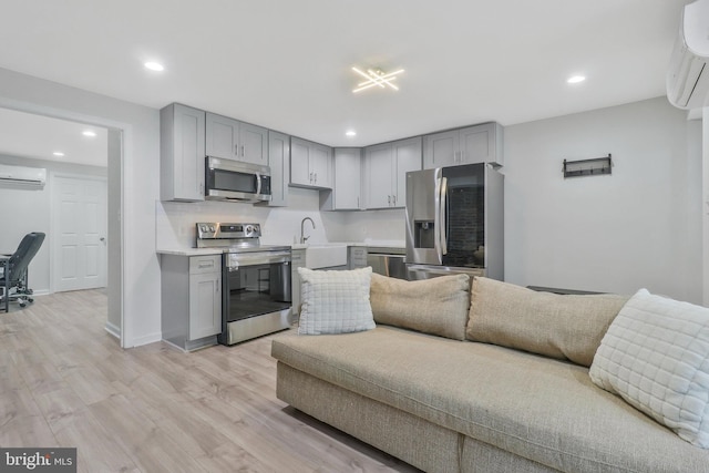 kitchen featuring gray cabinetry, light wood-type flooring, appliances with stainless steel finishes, and a wall mounted air conditioner