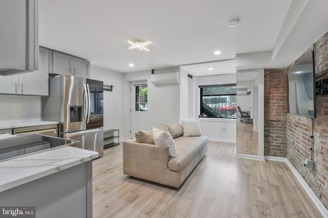 kitchen with light hardwood / wood-style flooring, stainless steel fridge with ice dispenser, an AC wall unit, gray cabinets, and tasteful backsplash