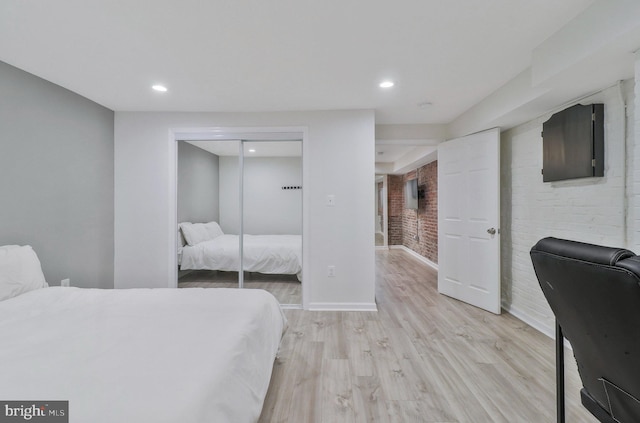 bedroom featuring brick wall, a closet, and light hardwood / wood-style floors