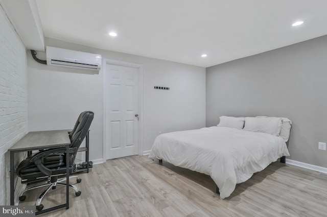 bedroom with a wall mounted air conditioner and light hardwood / wood-style floors