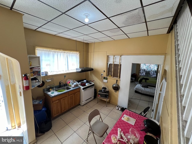 kitchen with light tile patterned flooring, a drop ceiling, sink, and white stove