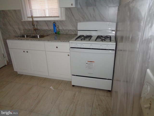 kitchen featuring light tile patterned floors, sink, white cabinetry, white gas stove, and light stone counters