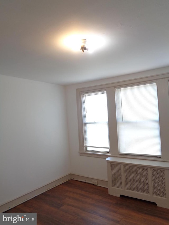 empty room featuring radiator heating unit and dark wood-type flooring