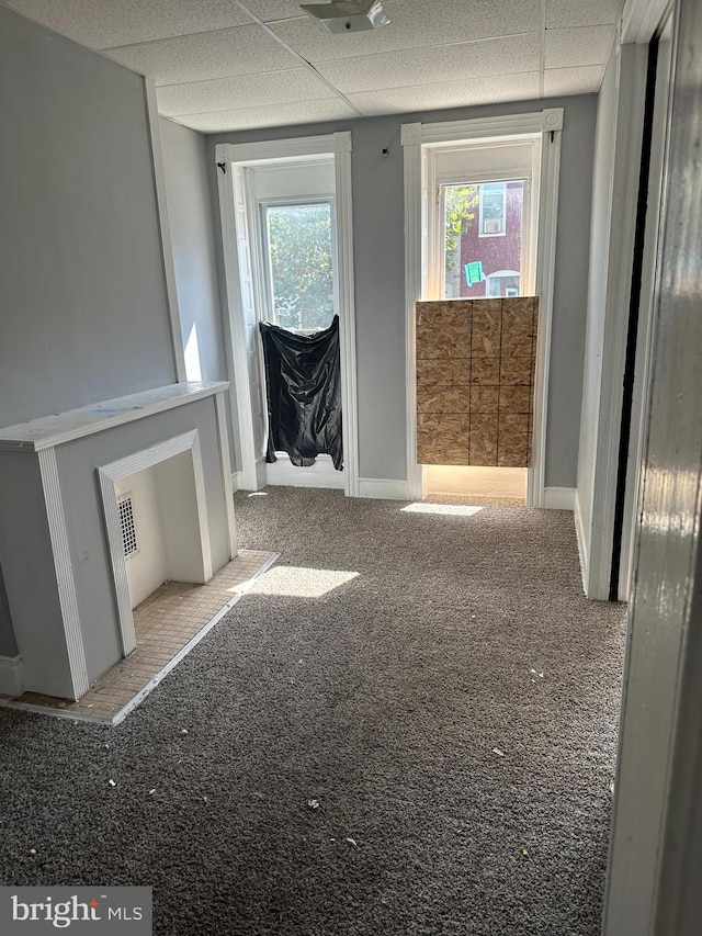 interior space with a paneled ceiling and light carpet