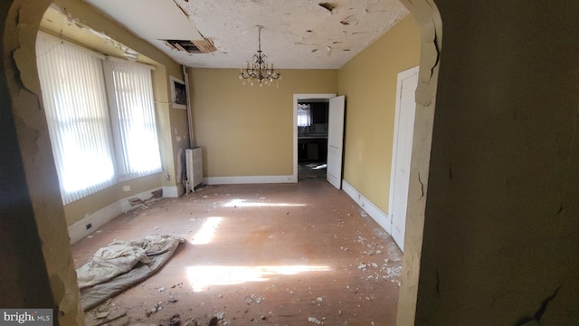 unfurnished dining area with visible vents, radiator, baseboards, and an inviting chandelier