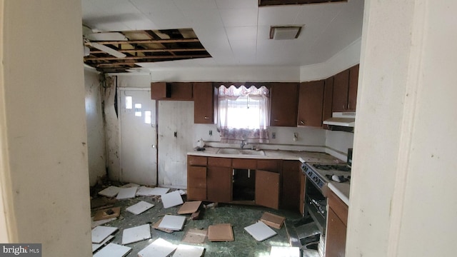 kitchen with under cabinet range hood, gas range, light countertops, and a sink