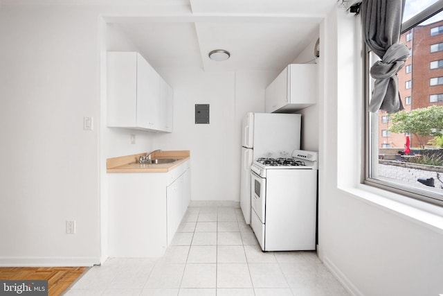 kitchen with white gas range, light tile patterned floors, sink, and white cabinets