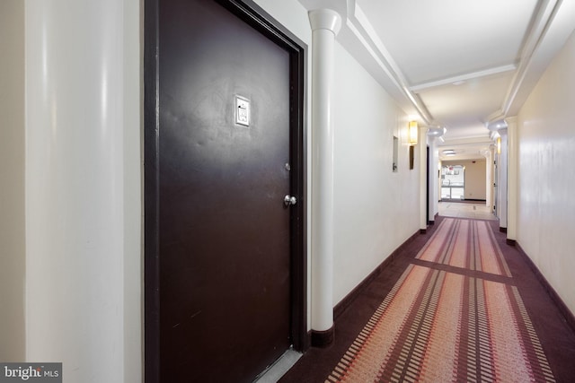 hallway with ornamental molding, decorative columns, and carpet flooring