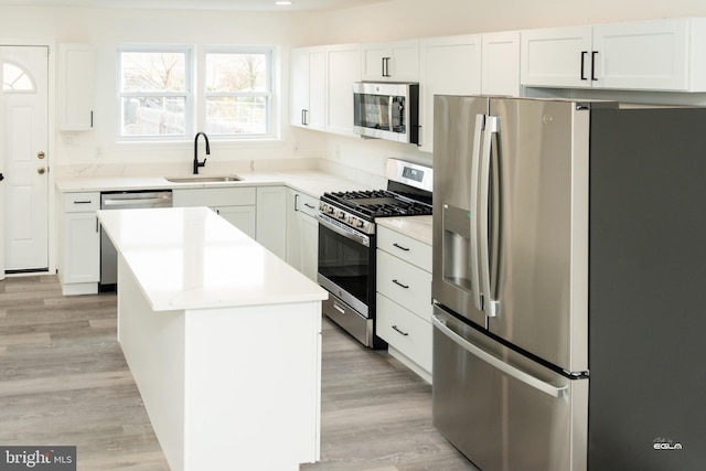 kitchen with white cabinets, a kitchen island, sink, and stainless steel appliances