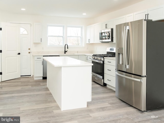 kitchen featuring sink, light hardwood / wood-style flooring, appliances with stainless steel finishes, a kitchen island, and white cabinetry