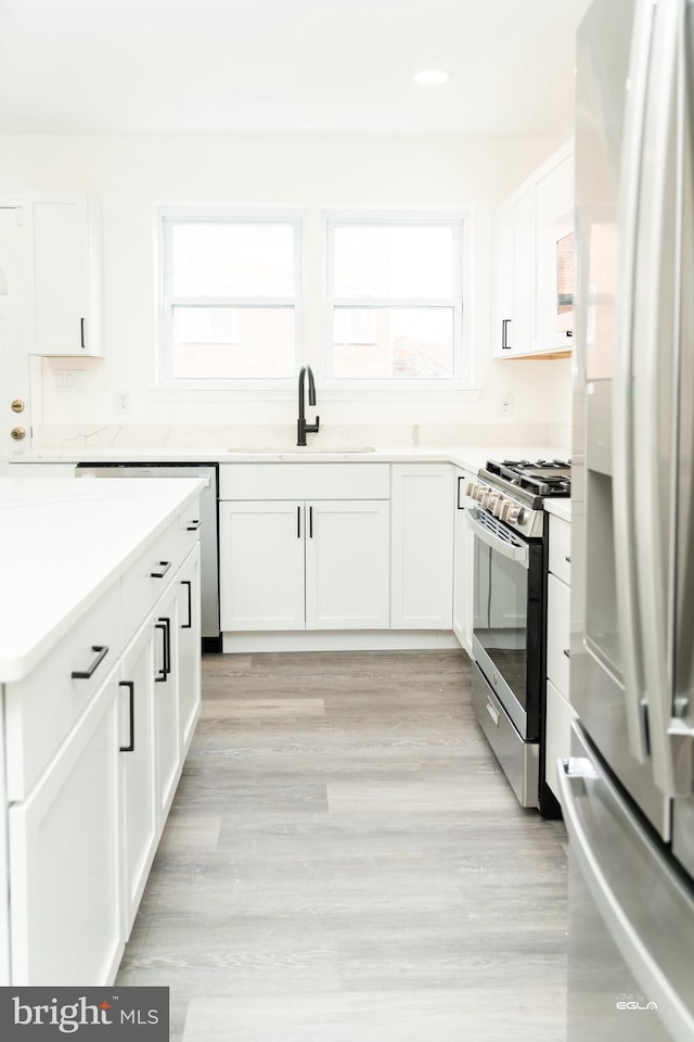 kitchen featuring white cabinets, a healthy amount of sunlight, sink, and stainless steel appliances