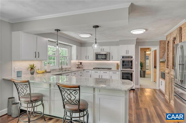 kitchen featuring hardwood / wood-style floors, appliances with stainless steel finishes, a kitchen breakfast bar, and kitchen peninsula