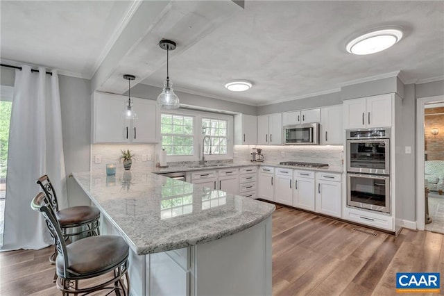 kitchen featuring appliances with stainless steel finishes, tasteful backsplash, kitchen peninsula, and a kitchen breakfast bar