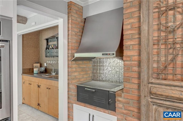 kitchen featuring light carpet, brick wall, sink, wall chimney exhaust hood, and tasteful backsplash