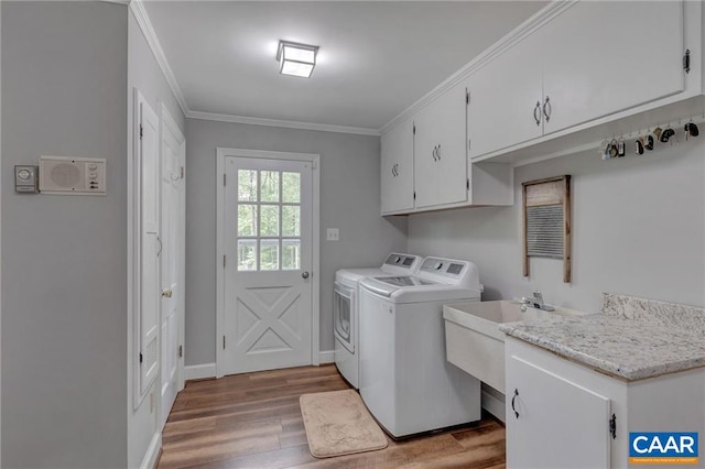 laundry area featuring ornamental molding, cabinets, separate washer and dryer, and wood-type flooring