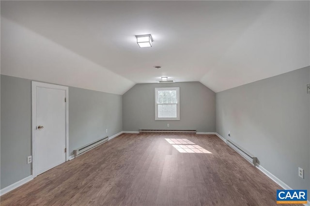 additional living space featuring lofted ceiling, hardwood / wood-style flooring, and a baseboard radiator