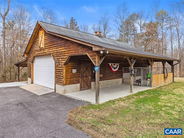 exterior space featuring a garage, a front lawn, and an outbuilding