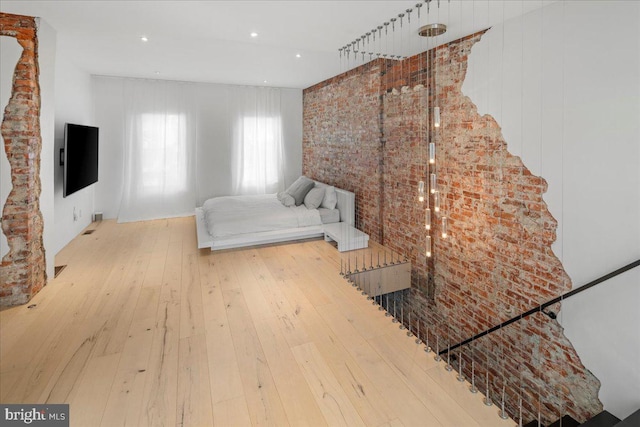 bedroom with light hardwood / wood-style flooring and brick wall