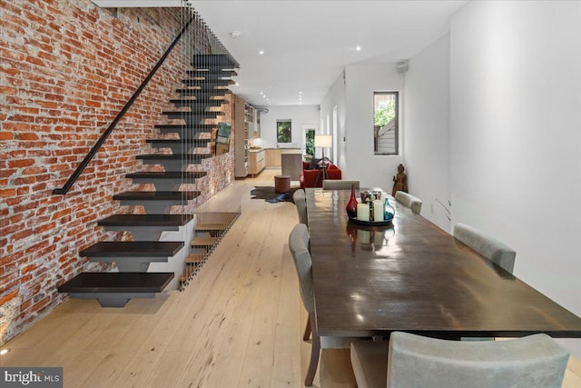 dining room with light hardwood / wood-style flooring and brick wall