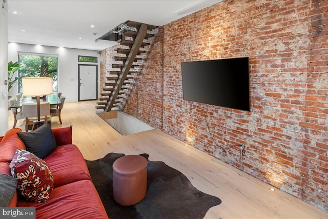 living room with light hardwood / wood-style floors and brick wall