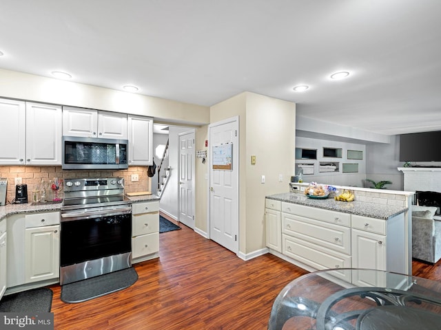 kitchen with white cabinets, backsplash, stainless steel appliances, and hardwood / wood-style flooring