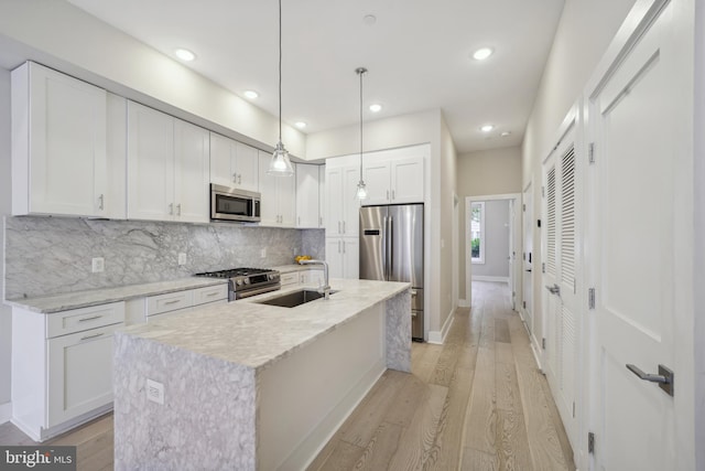 kitchen with a kitchen island with sink, decorative light fixtures, white cabinets, and appliances with stainless steel finishes