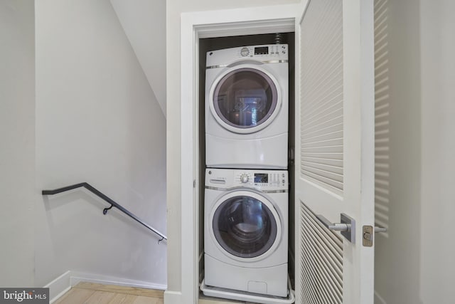 clothes washing area featuring light hardwood / wood-style flooring and stacked washer and clothes dryer