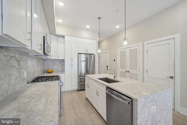 kitchen with decorative backsplash, white cabinetry, appliances with stainless steel finishes, light wood-type flooring, and sink