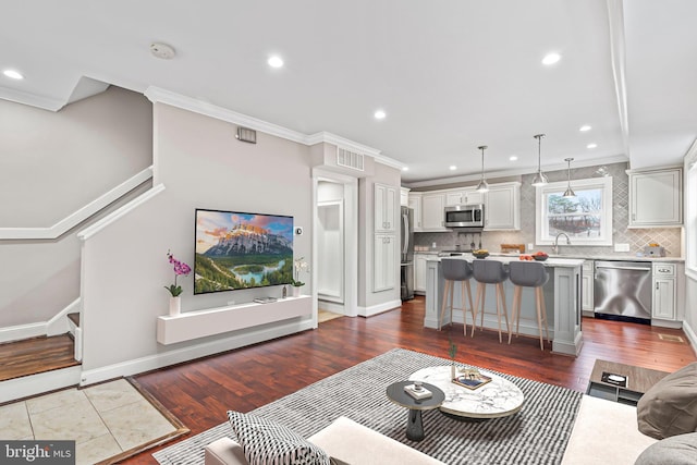 living room with sink, crown molding, and hardwood / wood-style floors