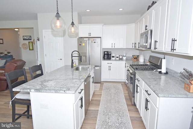 kitchen featuring pendant lighting, a kitchen breakfast bar, stainless steel appliances, and a kitchen island with sink