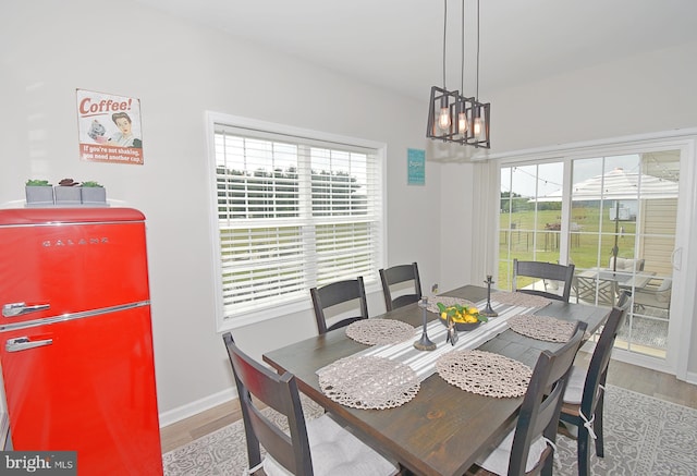 dining space with a healthy amount of sunlight, light wood-type flooring, and an inviting chandelier