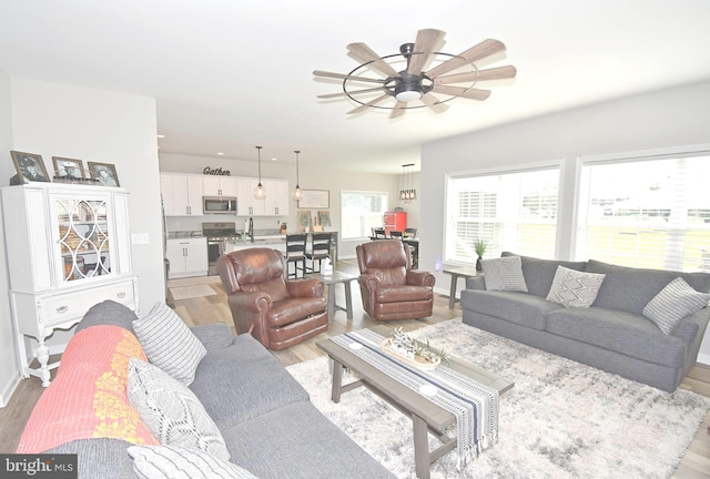 living room with ceiling fan, light wood-type flooring, and sink